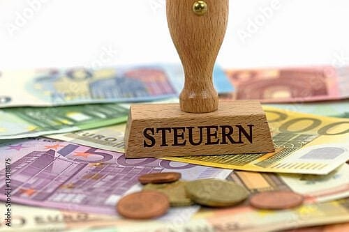 Auf diesem Bild ist ein Stempel mit der Aufschrift Steuern zu sehen, welcher auf Geldscheinen steht