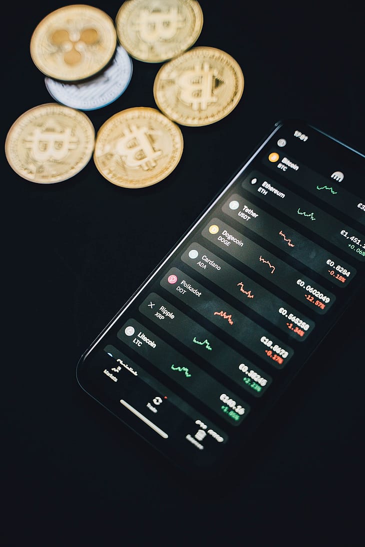 Auf diesem Bild sind physische Bitcoins zu sehen und ein Handy auf dem ein Kryptowallet abgebildet ist